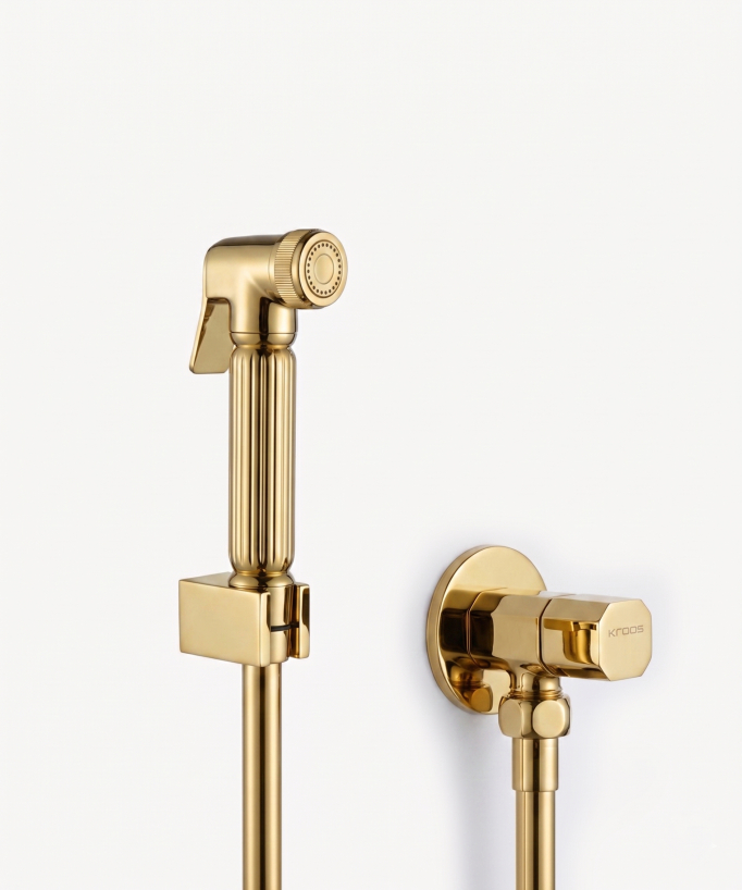 Douchette pour WC doré, avec un flexible de même couleur, reposant sur un support mural assorti. 